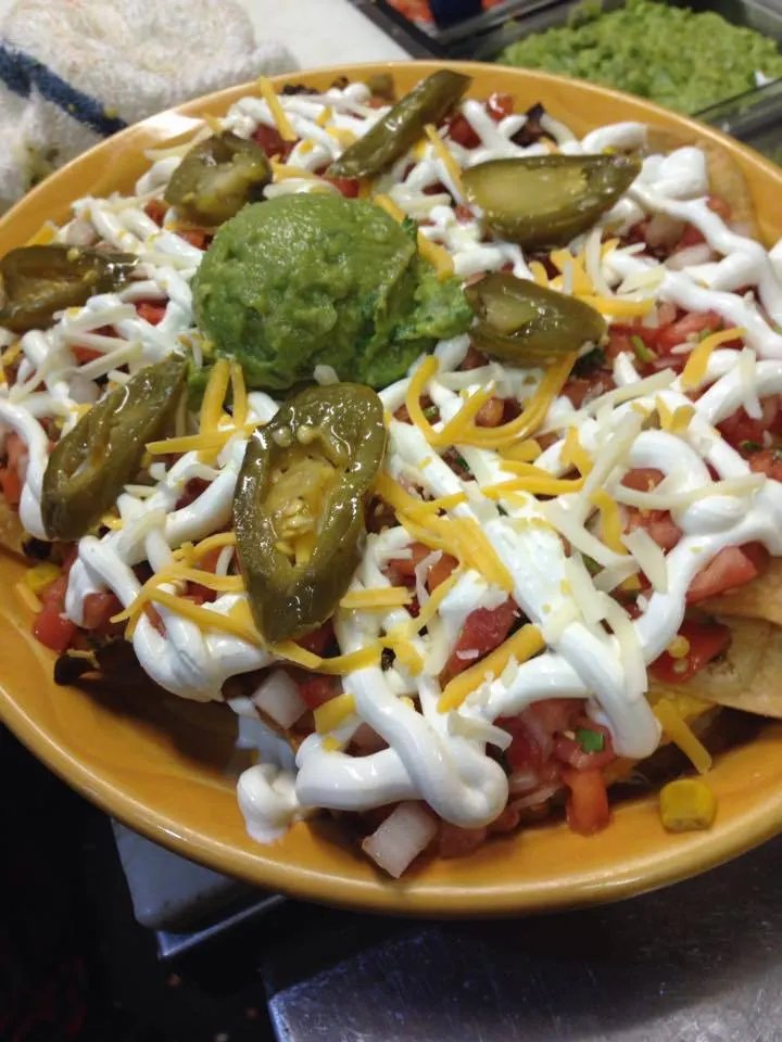 Nachos topped with cheese, sour cream and guacamole